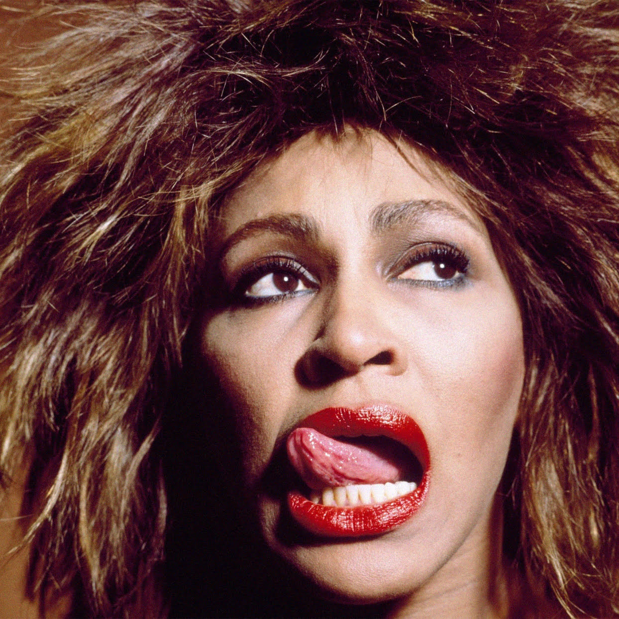 Portrait of young Tina Turner, licking her red lips